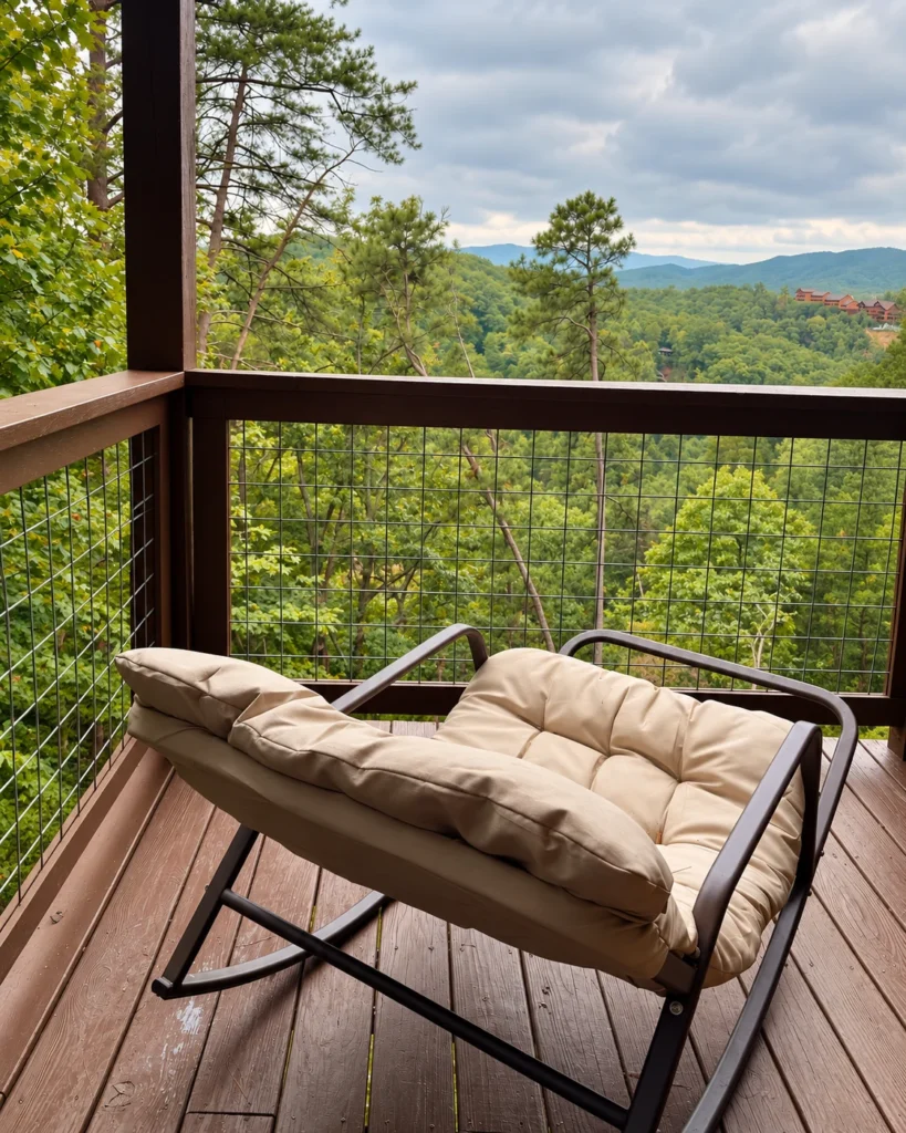 A padded rocker on the covered deck, with a wooded mountain outlook.