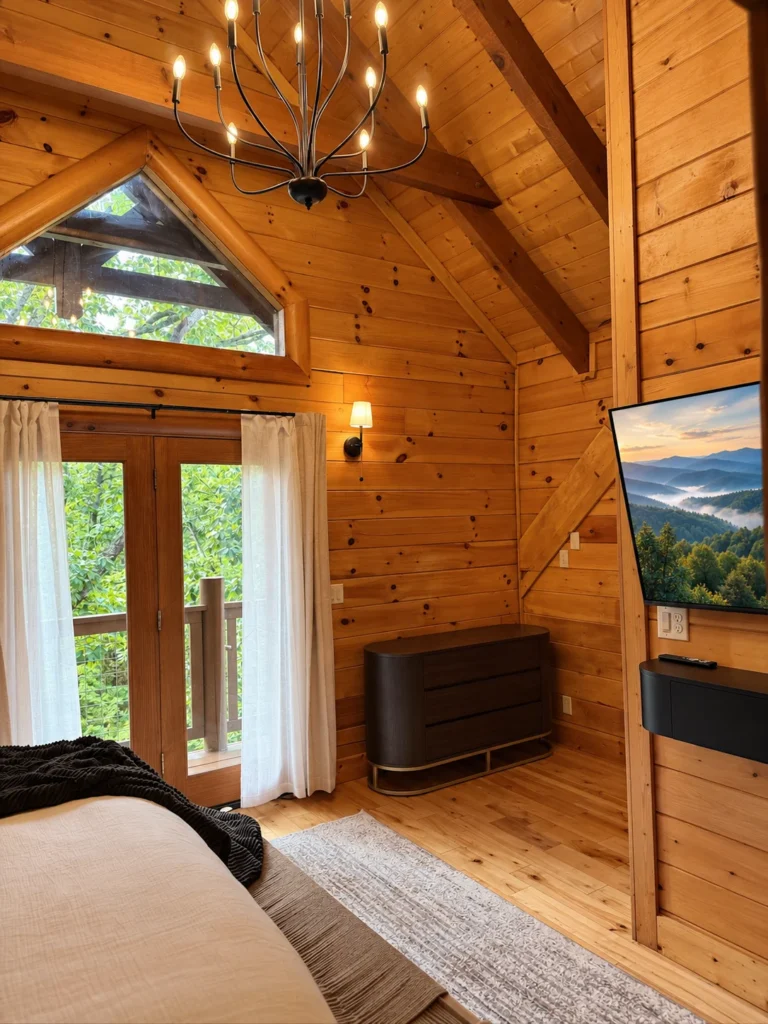Tall timber ceilings and glazed deck doors beside a king bed.