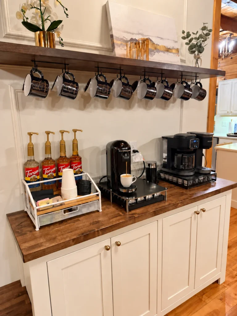 Coffee makers, mugs and flavoring syrups arranged beside the dining area.
