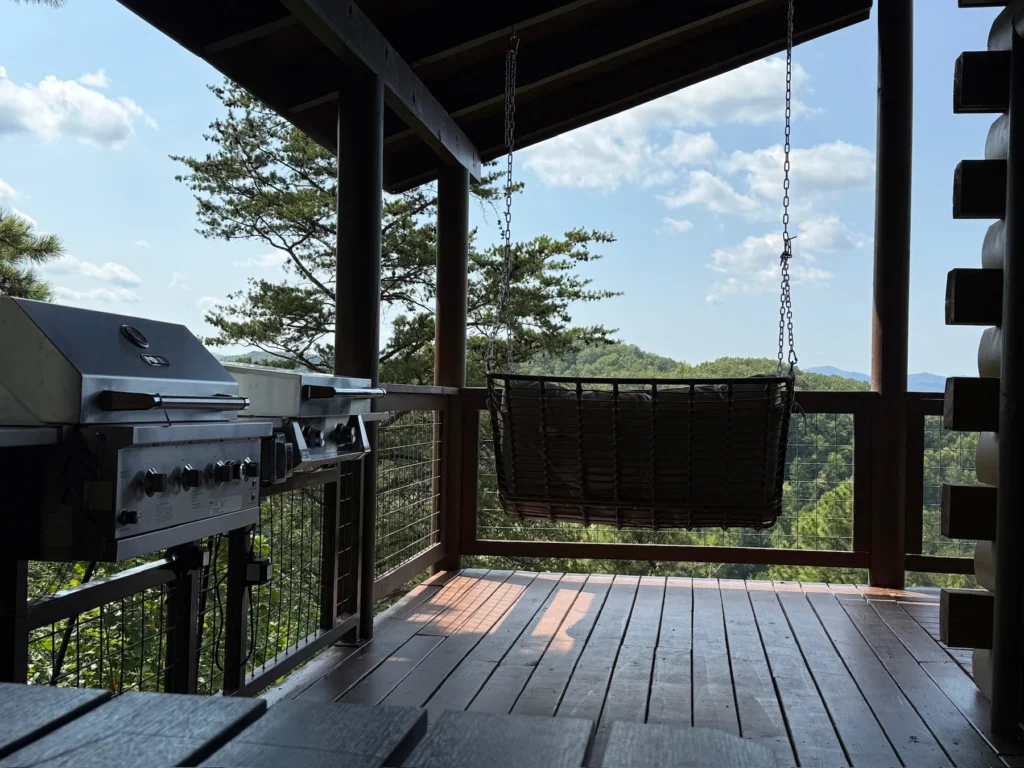 The grill and griddle beside a hanging seat on the covered deck.