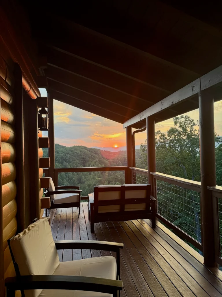 Cushioned chairs face the setting sun and wooded hills.