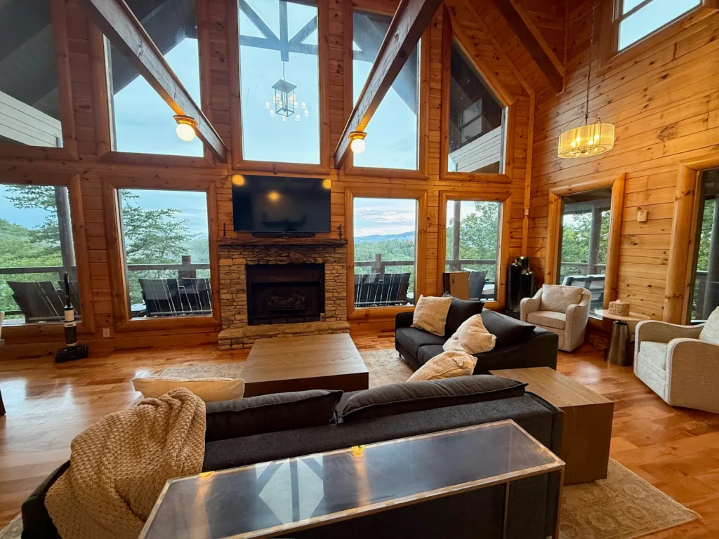 A stone fireplace, tall windows and comfortable seating beneath the timber ceiling.