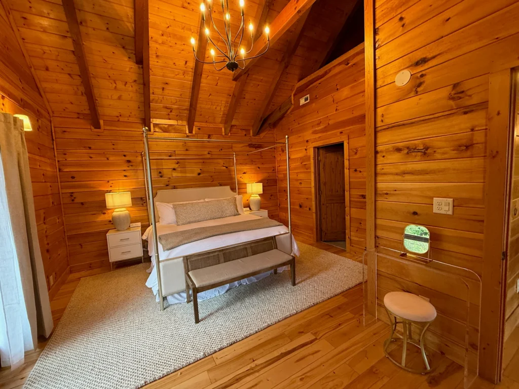 The four-poster king bed and matching bench beneath a vaulted timber ceiling.