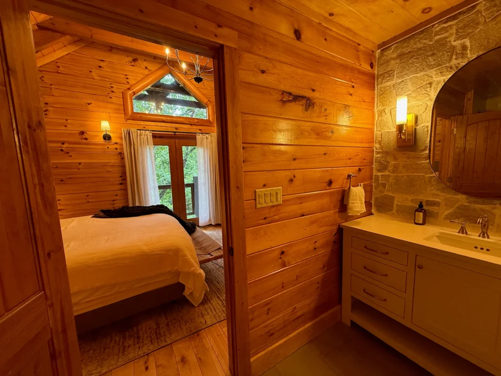 The king bed sits beside a bathroom vanity and doors to the covered deck.