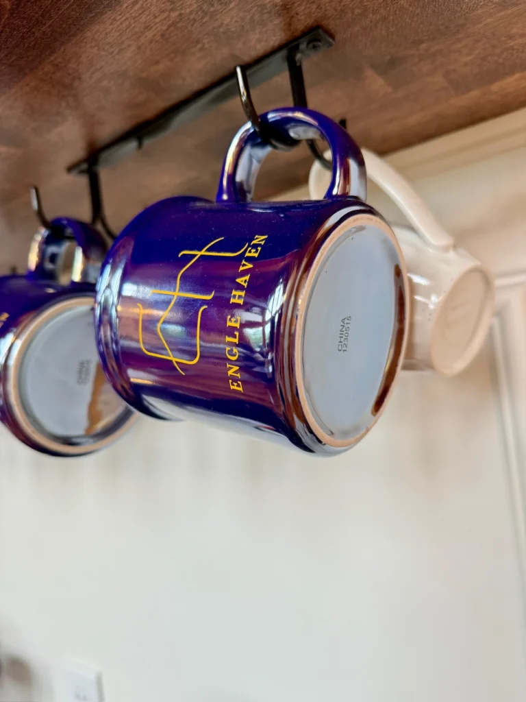 Cabin mugs hang from hooks at the coffee bar.