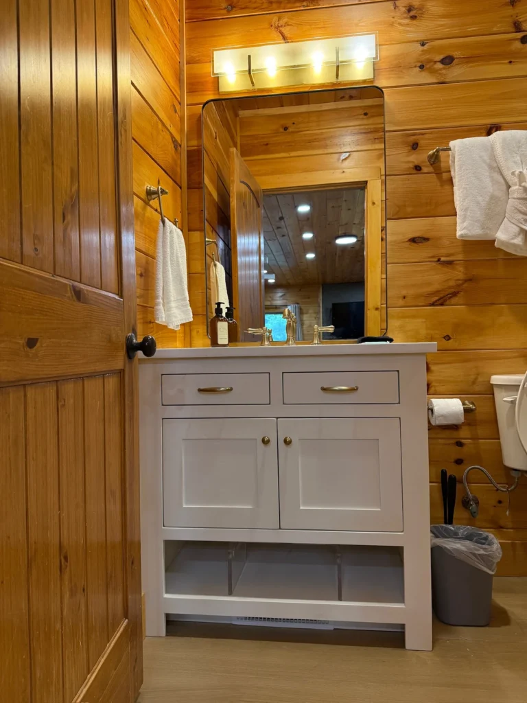 A white vanity and large mirror in the timber-lined bathroom.