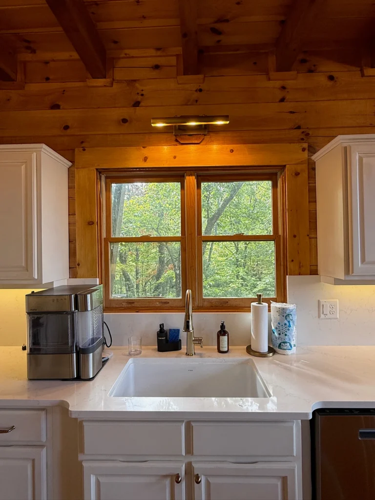The main kitchen sink sits beneath a window facing the trees.