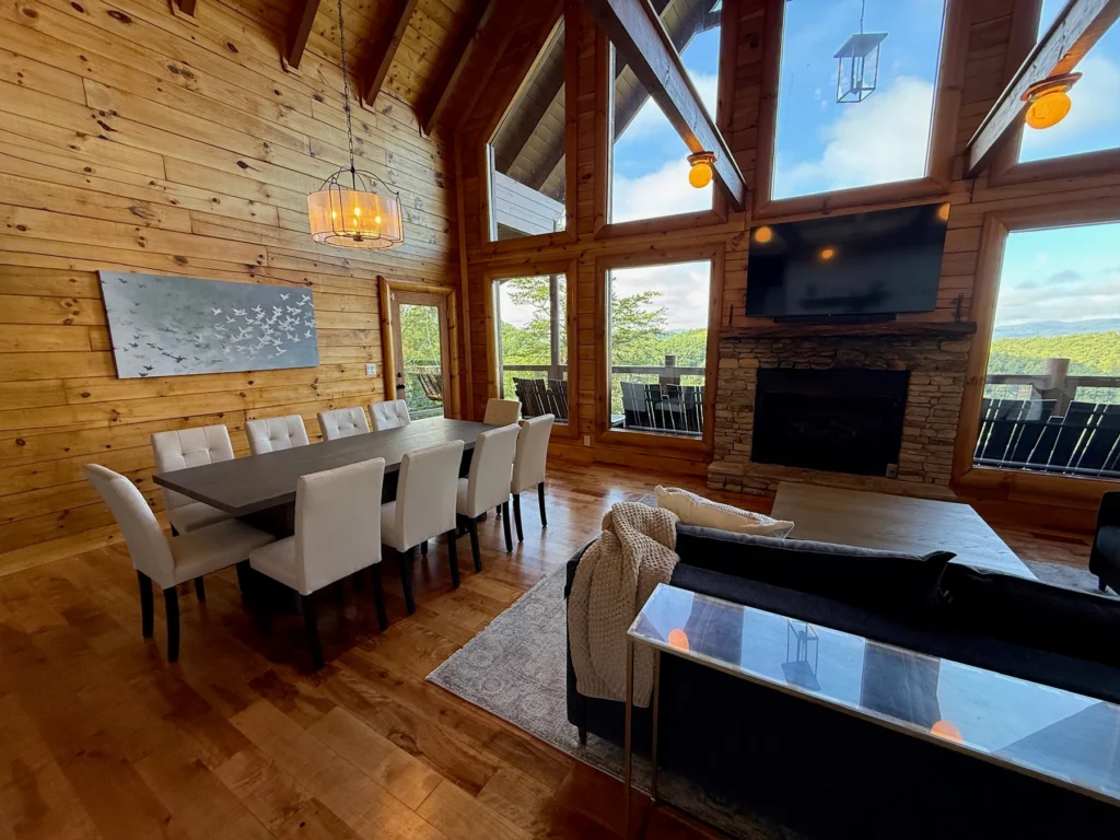 The dining table beside the fireplace and tall mountain-view windows.