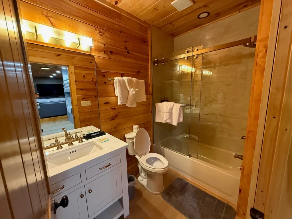 A white vanity, bathtub and glass shower enclosure in the lower-level bathroom.