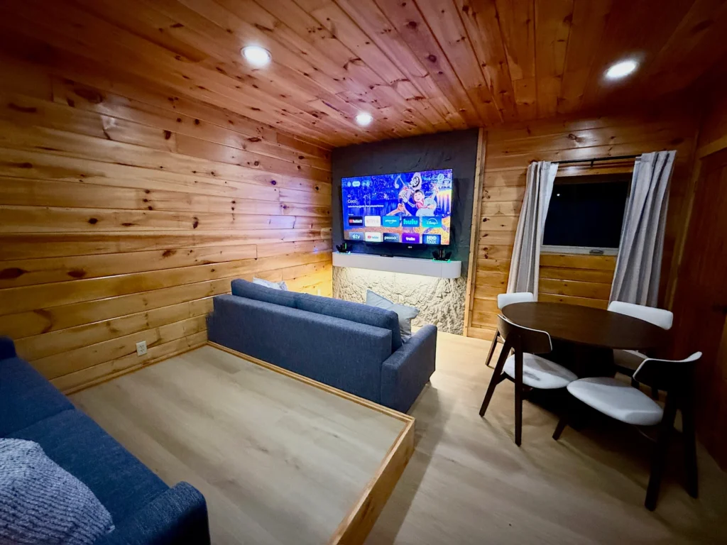 Tiered sofa seating faces the 75-inch TV, with a game table beside it.