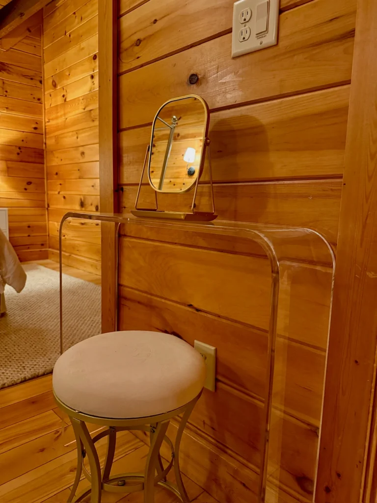 A makeup vanity with a mirror and upholstered stool in the bedroom.