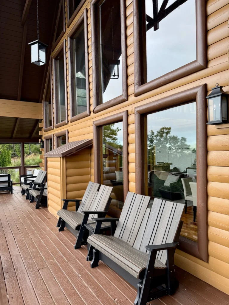 Rocking chairs sit beneath the covered deck beside the great-room windows.