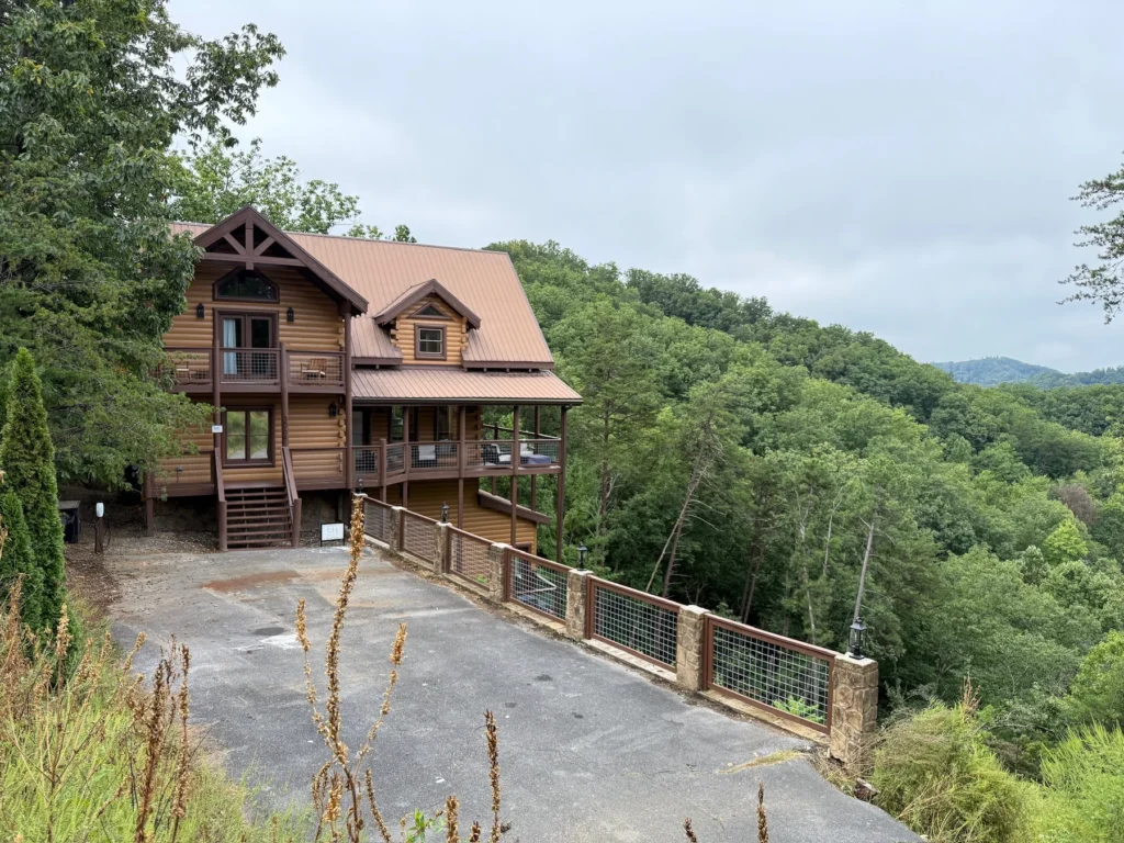 The cabin and paved driveway on a wooded hillside.