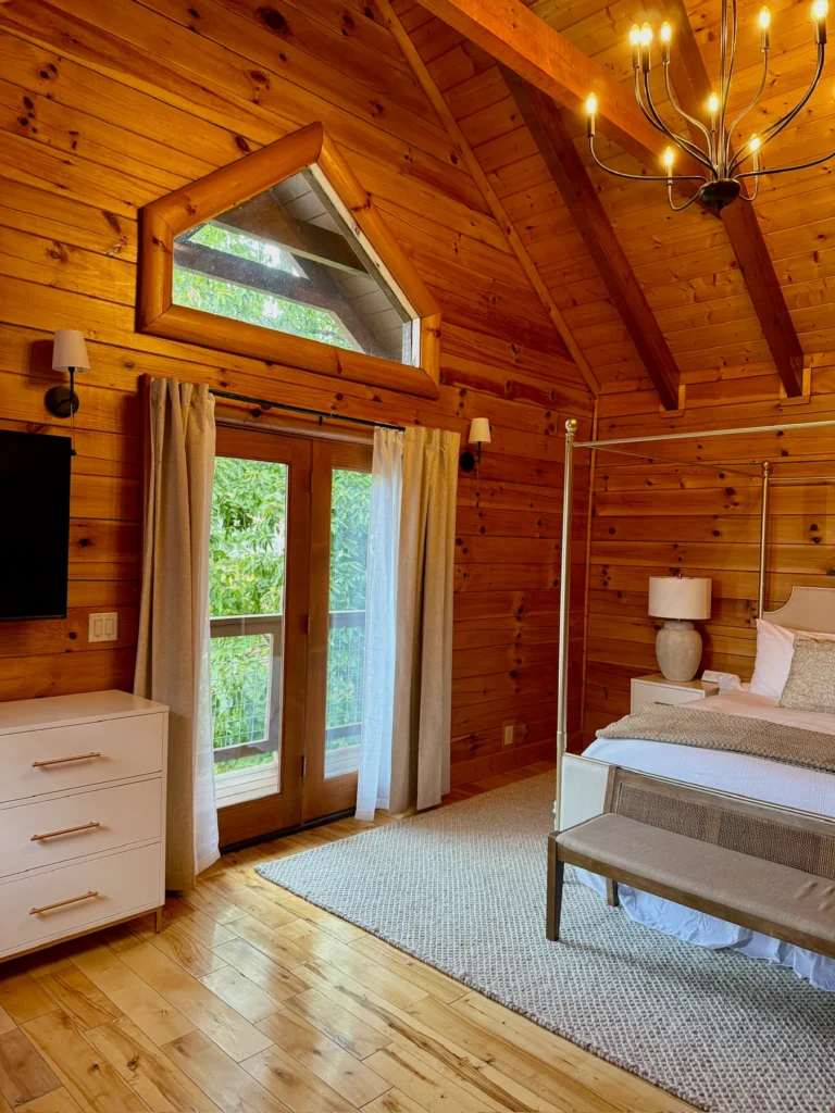 The four-poster bedroom’s glazed doors open toward the covered deck.