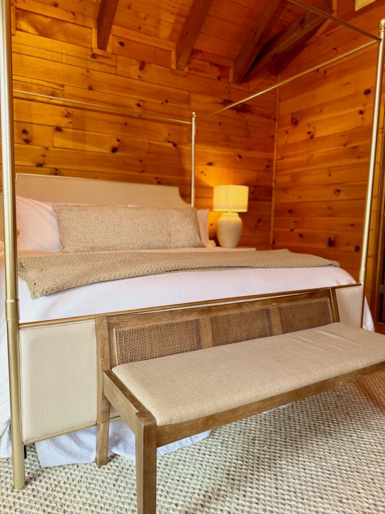 An upholstered bench and bedside table beneath warm lamps in the king bedroom.