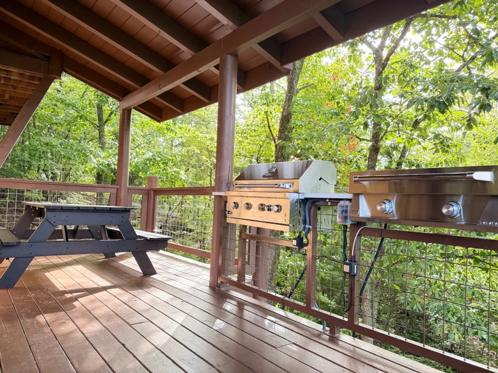 The grill and griddle beside a picnic table on the covered deck.
