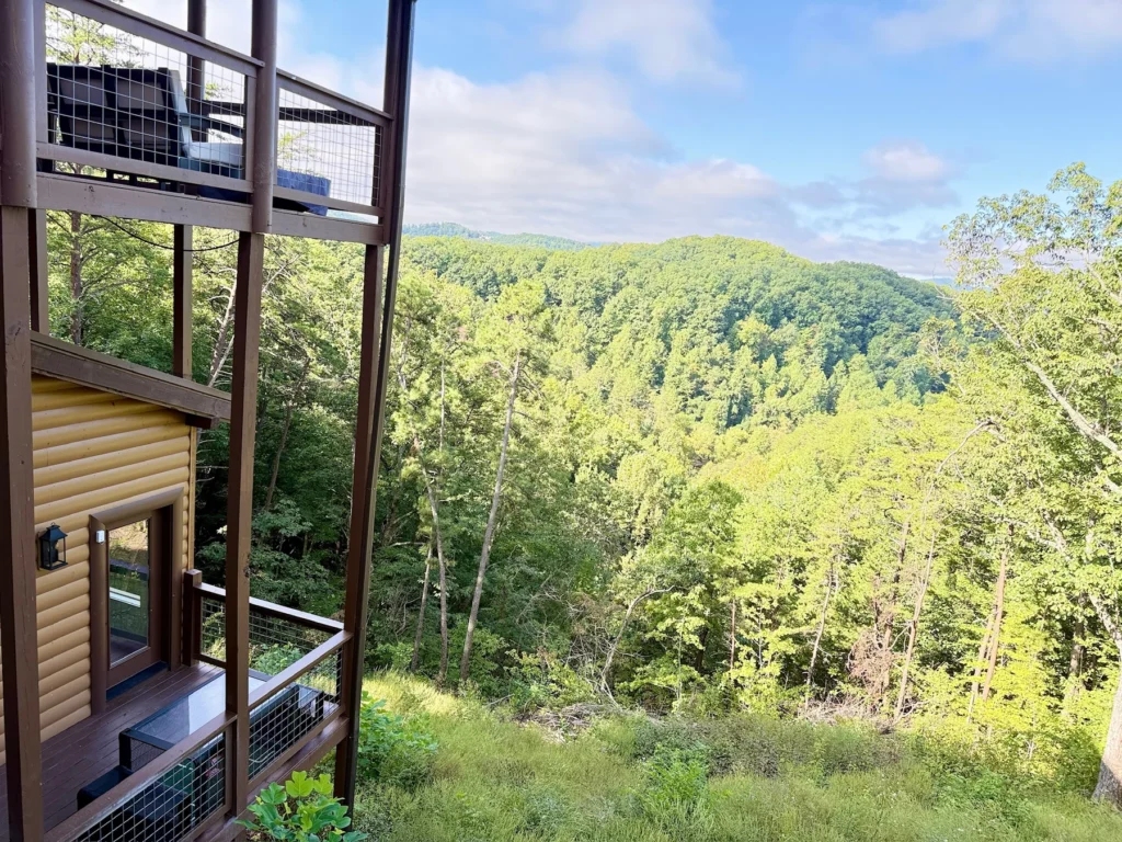 A view between the cabin’s timber posts toward wooded hills.