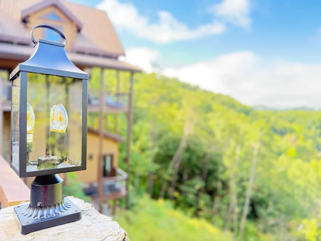 A deck lantern beside the cabin’s timber exterior and wooded setting.