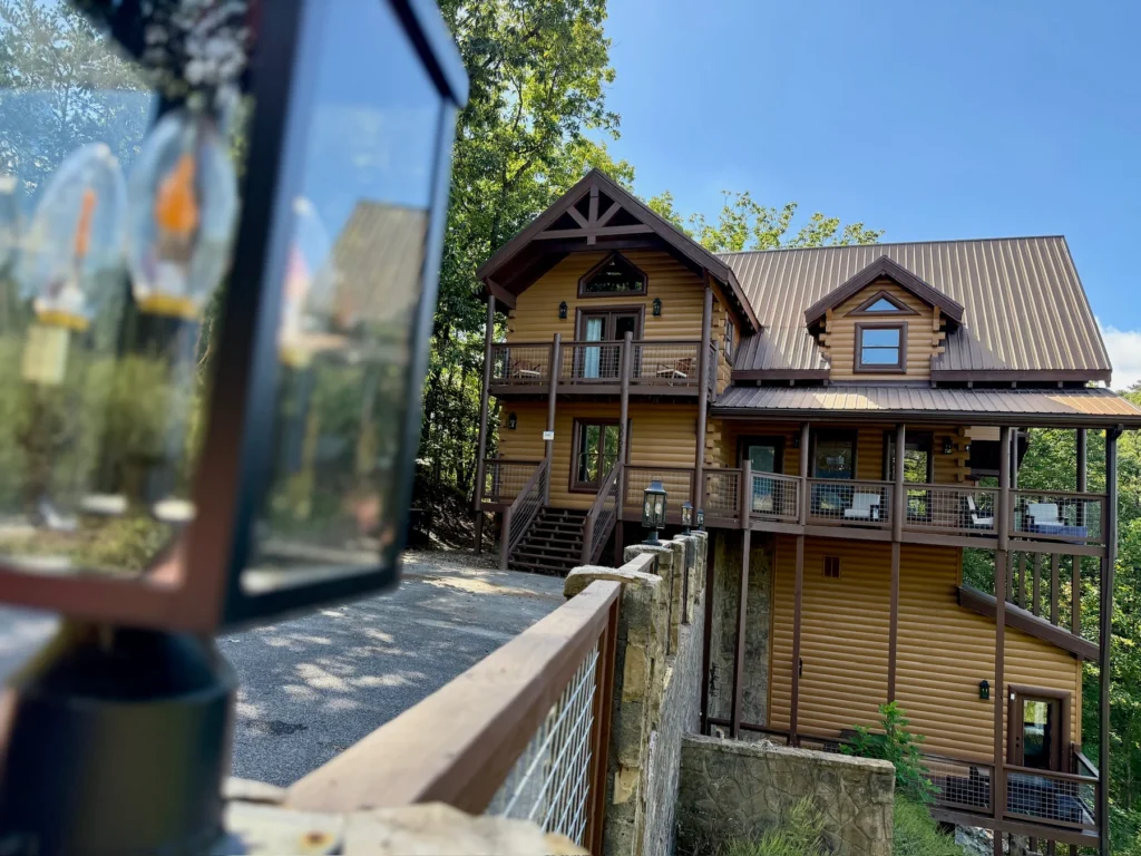 A lantern in the foreground frames the cabin and paved arrival area.
