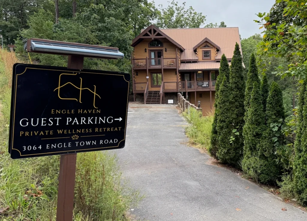 Engle Haven Guest Parking sign beside the paved driveway leading to the log cabin.