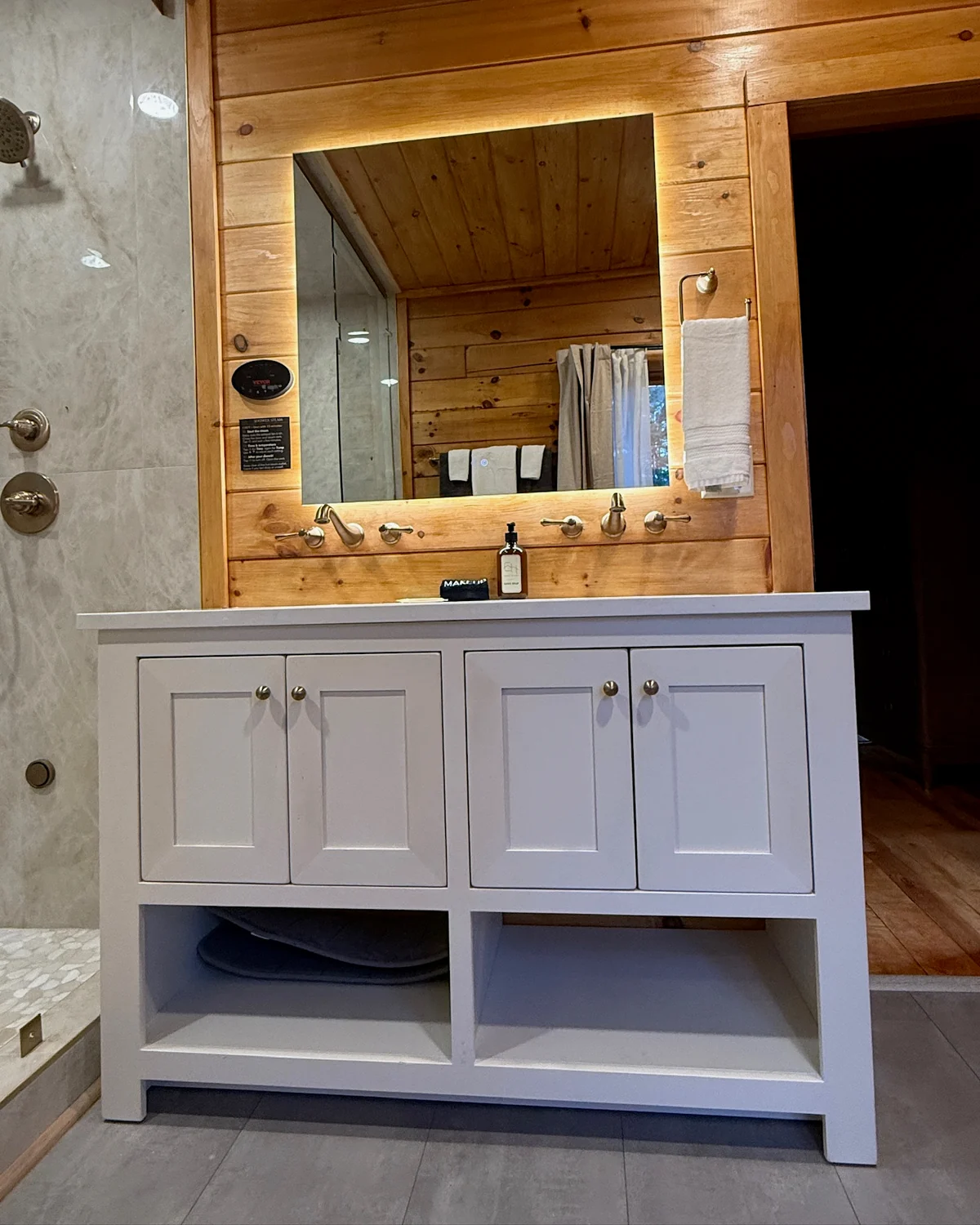 A white bathroom vanity with a sink, cabinet doors and open shelves beneath a wall mirror.