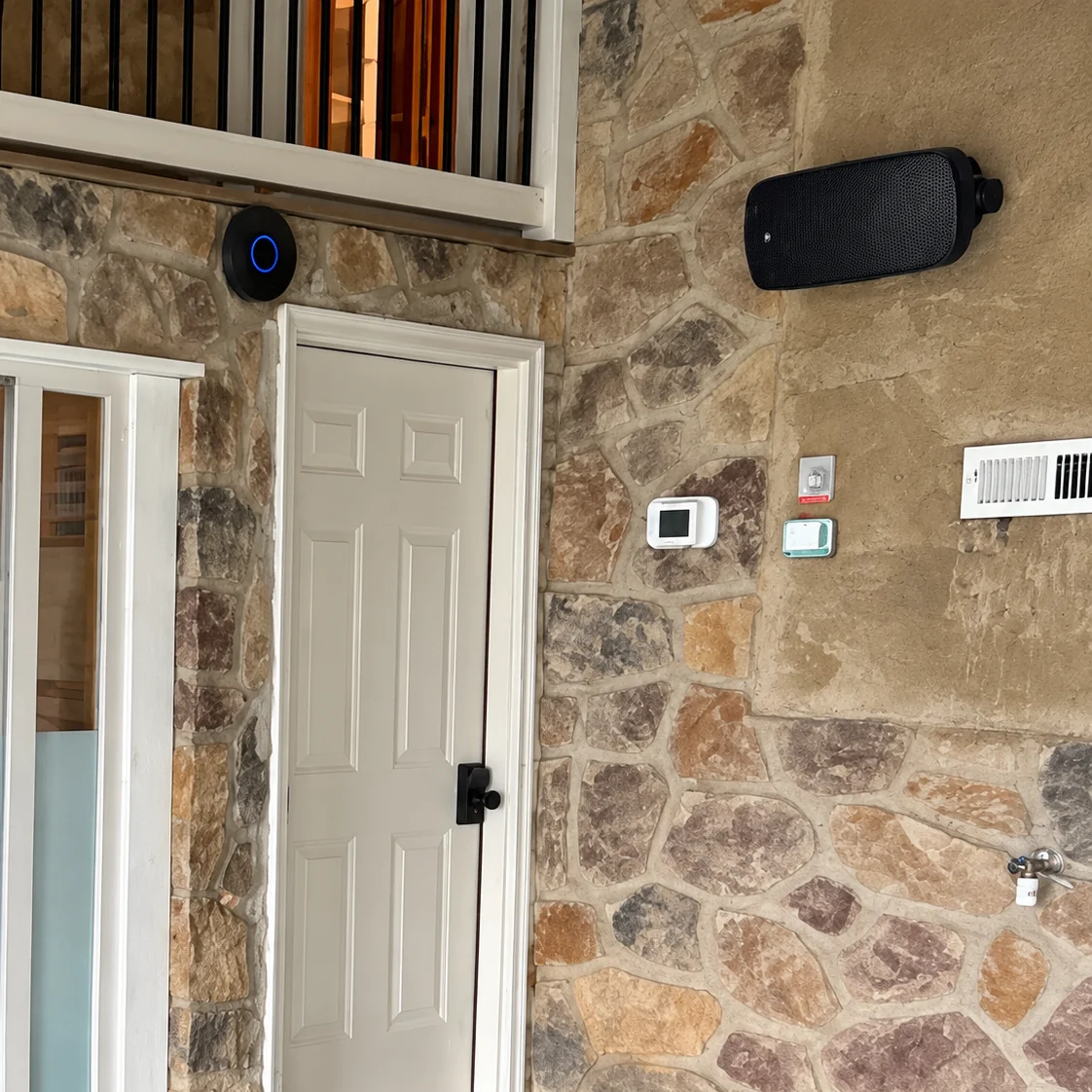 A black wall-mounted speaker above the stone wall and doorway of the indoor pool room.