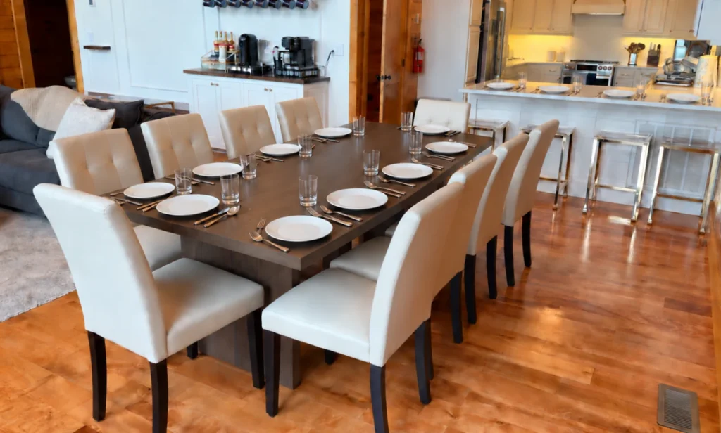 Dining table set with white plates and upholstered chairs beside the kitchen.