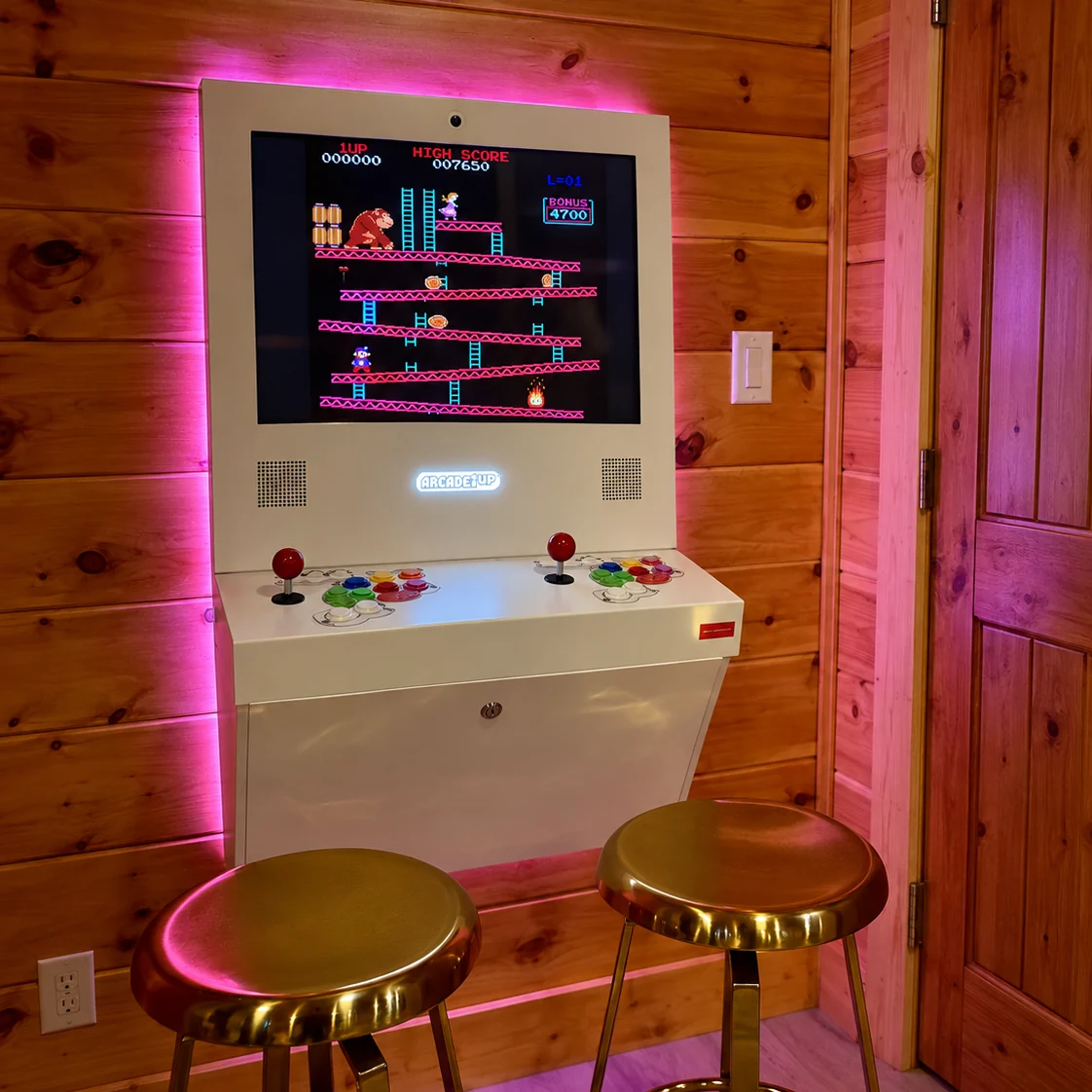 Classic arcade cabinet with a game on screen and two gold stools.