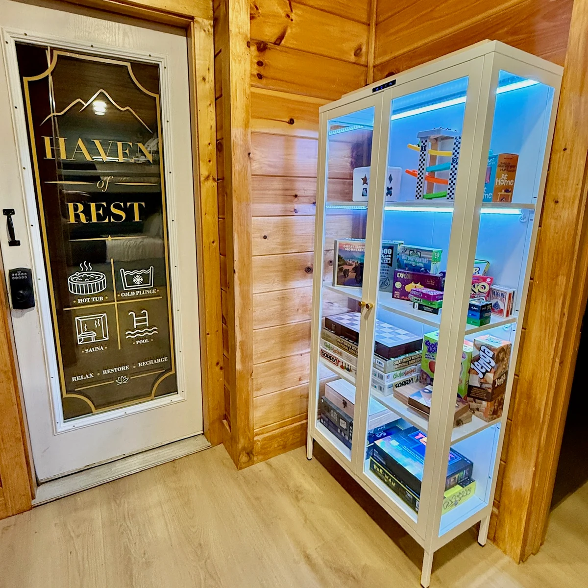 An illuminated glass-front cabinet stocked with board games.