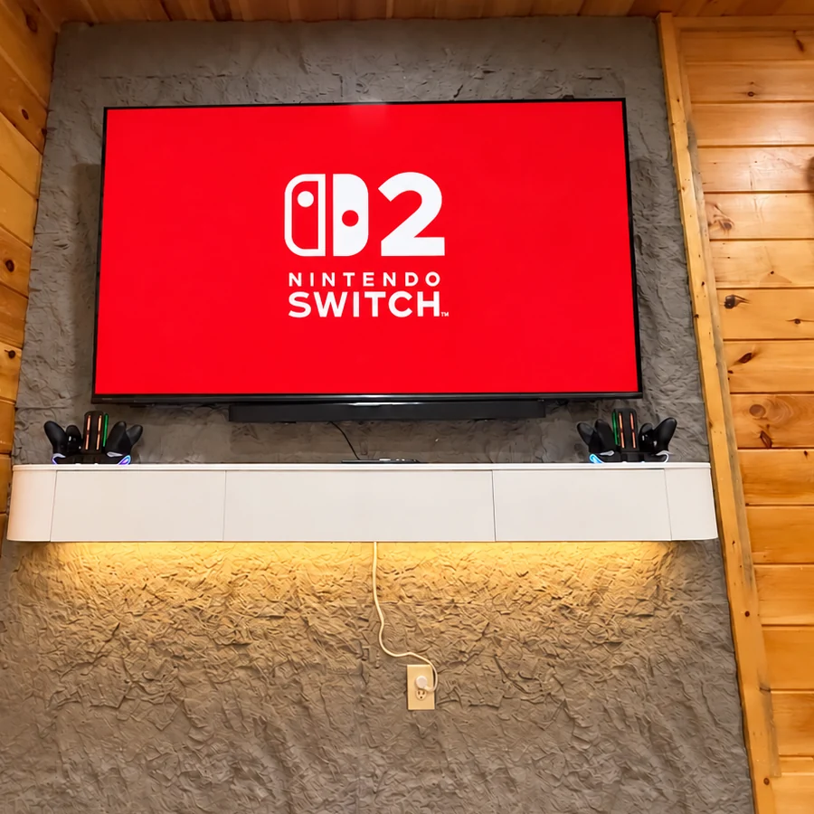 Nintendo Switch 2 on the television above a shelf with game controllers.