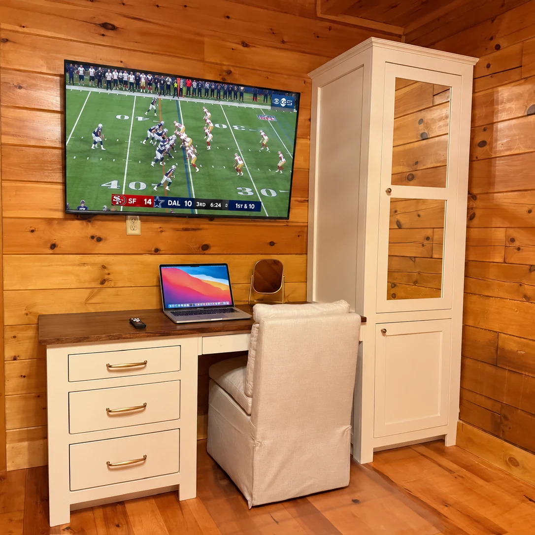 A dedicated desk and chair beneath a television showing a football game.
