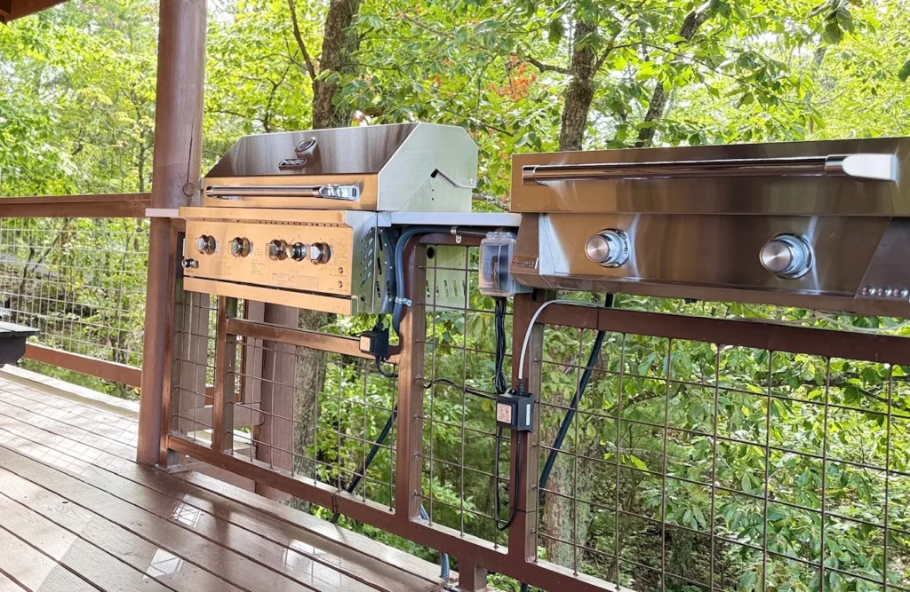 Built-in grill and griddle on a covered deck overlooking the trees.
