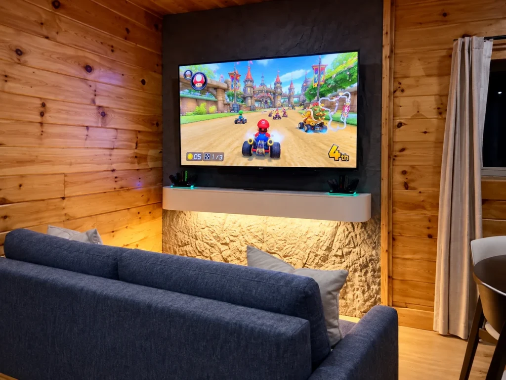 Large television showing a racing game above a lit shelf, with blue sofa seating in the foreground.