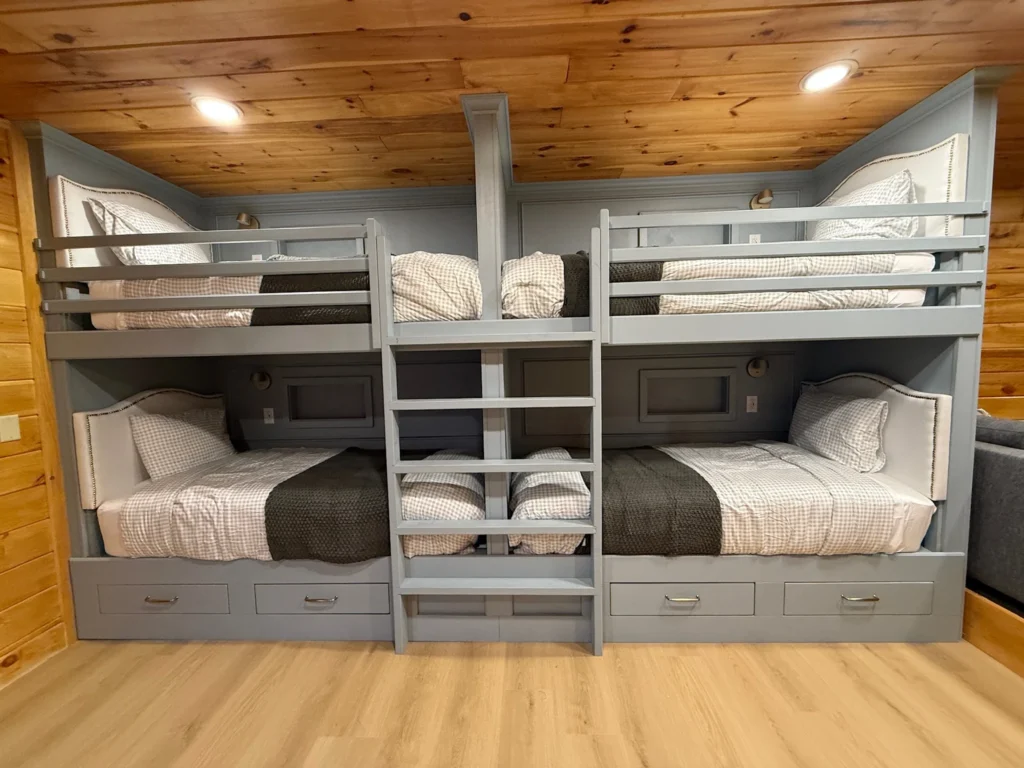 Four gray built-in bunks with a central ladder, individual reading lights and pale bedding.