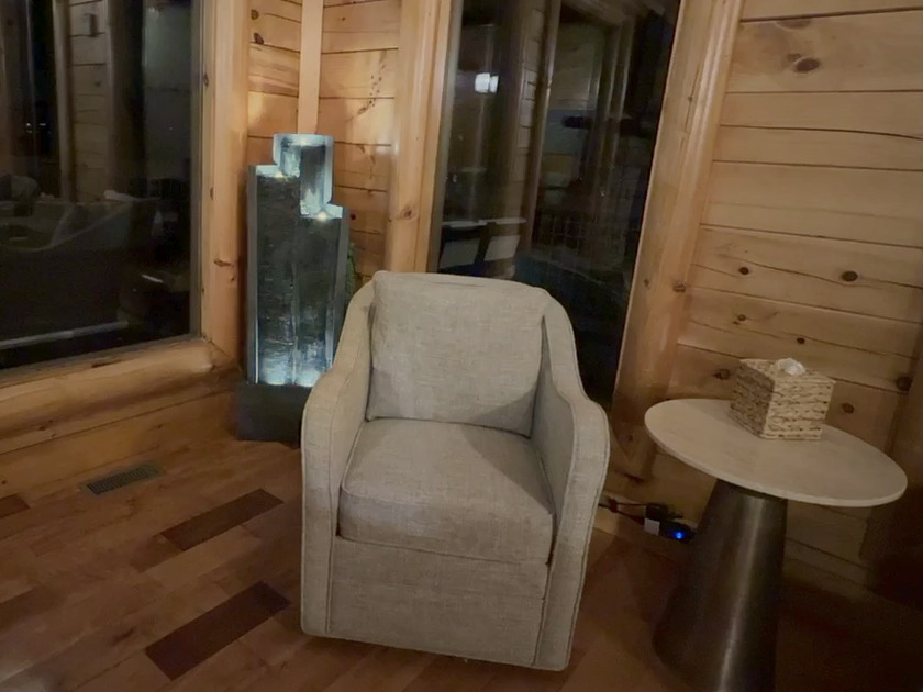 Illuminated water flowing beside a cushioned chair in Engle Haven’s timber-lined reading corner.