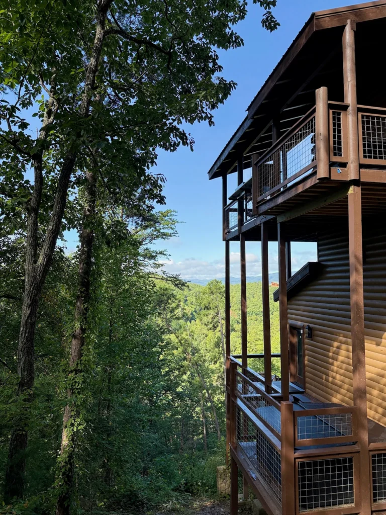 Multi-level cabin and covered decks framed by trees on a hillside.