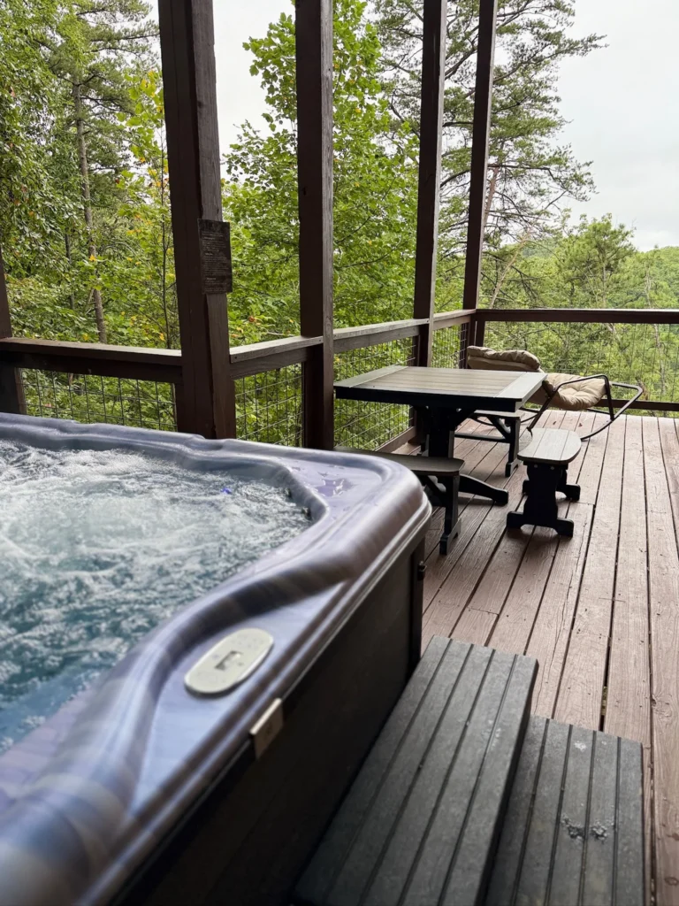 Hot tub beside a picnic table and cushioned chair on the covered deck.
