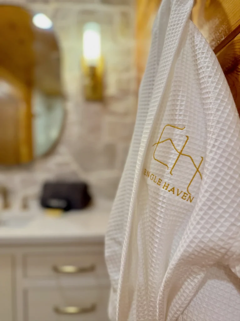 White Engle Haven robe in the foreground, with a softly blurred bathroom vanity behind it.